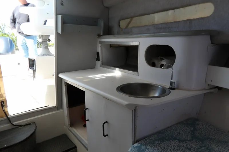 Slide: The Image of Interior of a 1993 Wahoo 2600 boat featuring a compact kitchenette with sink. - 22