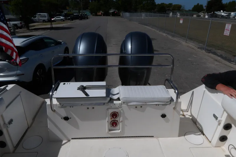 Slide: The Image of 1993 Wahoo 2600 boat with dual engines, docked near parked cars and American flag. - 26