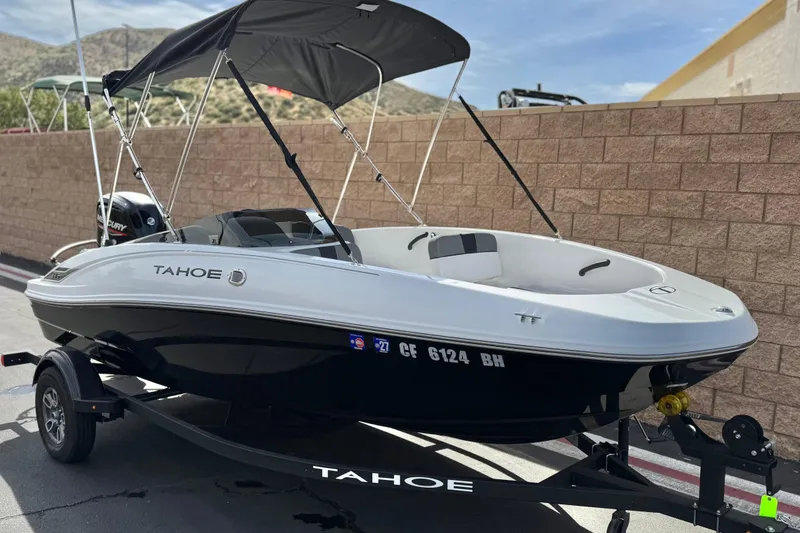 Slide: The Image of 2025 Tahoe T16 boat with canopy on trailer, parked outdoors. - 1