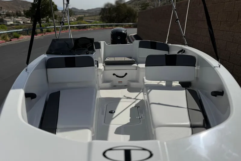 Slide: The Image of 2025 Tahoe T16 boat interior with seating and steering console, parked outdoors. - 10