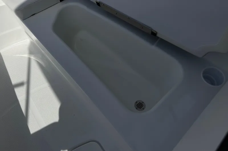 Slide: The Image of Open storage compartment in 2025 Tahoe T16 boat, featuring a drain and cup holder. - 15