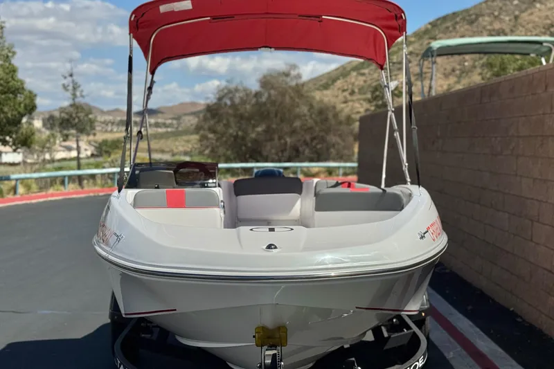 Slide: The Image of 2024 Tahoe T16 boat with red canopy, parked outdoors on a sunny day. - 2