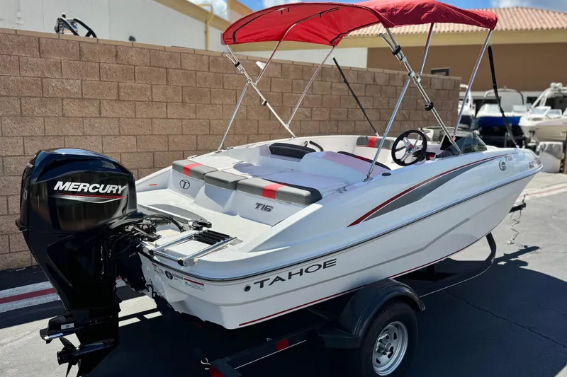 Slide: The Image of 2024 Tahoe T16 boat with Mercury engine and red canopy, parked outdoors. - 5