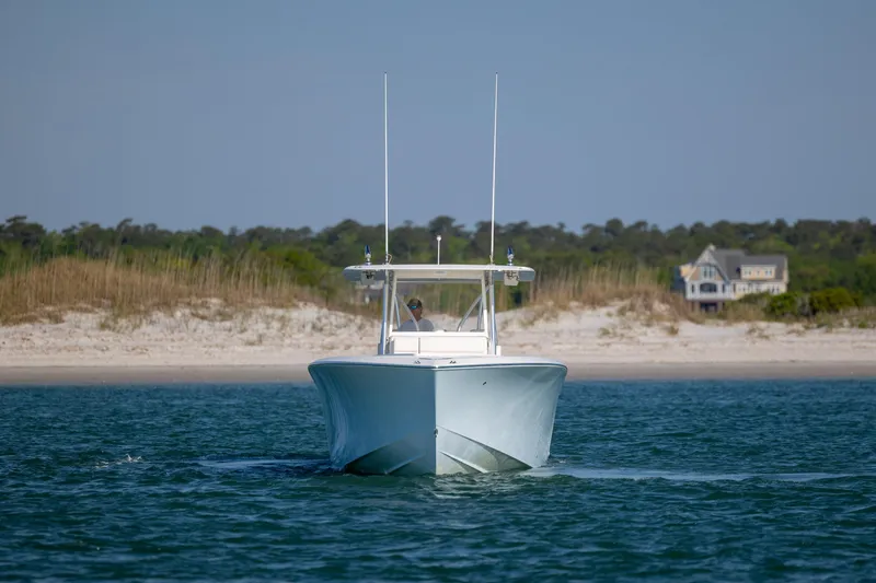 Slide: The Image of 2019 SeaVee 370Z boat cruising near a sandy shoreline with a house in the background. - 8