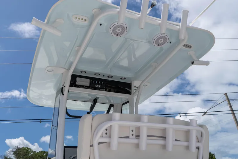 Slide: The Image of 2023 Sea Hunt Ultra 239 SE boat console with speakers and rod holders under a blue sky. - 17