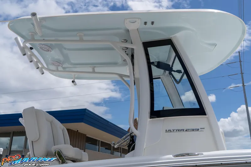 Slide: The Image of 2023 Sea Hunt Ultra 239 SE boat with T-top and seating, under a blue sky. - 19
