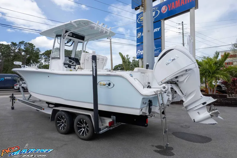Slide: The Image of 2023 Sea Hunt Ultra 239 SE boat on trailer, displayed outdoors near dealership signs. - 9