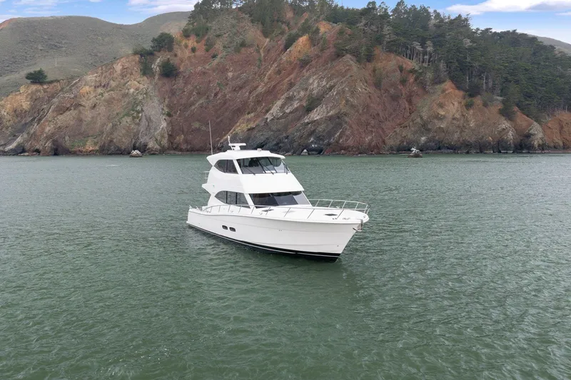 Slide: The Image of 2014 Maritimo M50 yacht on calm water with rocky hillside backdrop. - 5