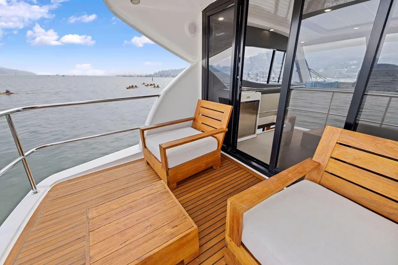 Slide: The Image of Luxury Maritimo M50 yacht deck with wooden seating, ocean view, and sliding glass doors. - 55