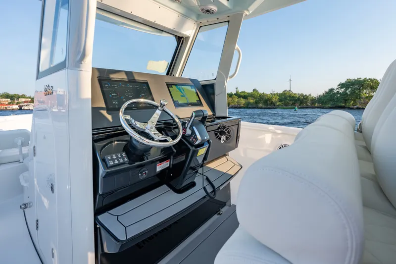 Slide: The Image of 2026 Everglades 335 Center Console boat interior with modern navigation system and steering wheel. - 11