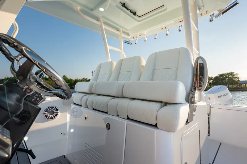 Slide: The Image of 2026 Everglades 335 Center Console boat interior with luxurious white seating and steering wheel. - 13