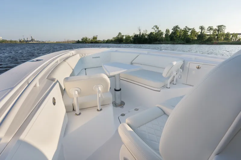 Slide: The Image of 2026 Everglades 335 Center Console boat interior with white seating and table on calm water. - 15