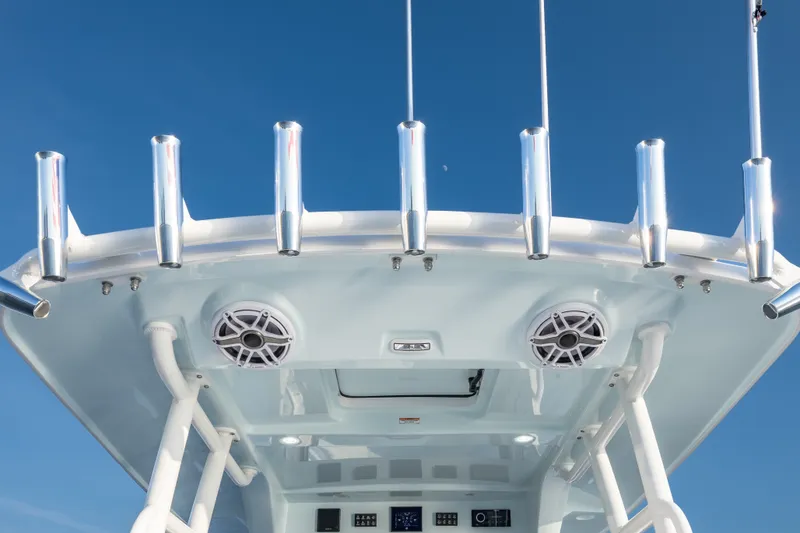 Slide: The Image of 2026 Everglades 335 Center Console boat with rod holders and speakers against blue sky. - 9