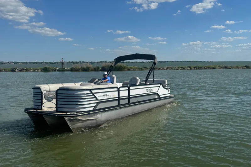 Slide: The Image of 2020 SunCatcher Elite 326 DLX SS pontoon boat cruising on a sunny lake. - 2