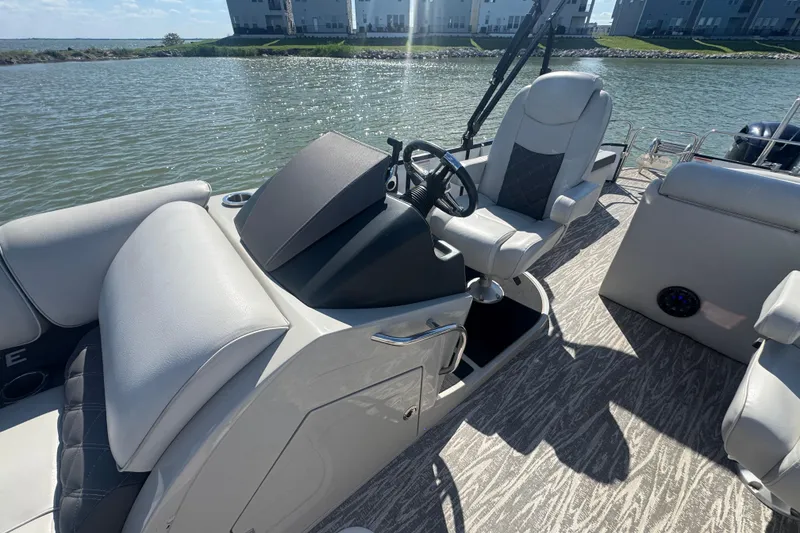 Slide: The Image of 2020 SunCatcher Elite 326 DLX SS boat interior with steering console and seating on water. - 20