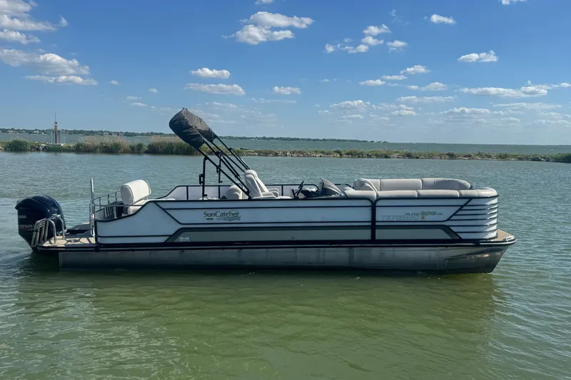 Slide: The Image of 2020 SunCatcher Elite 326 DLX SS pontoon boat on a calm lake under blue sky. - 6