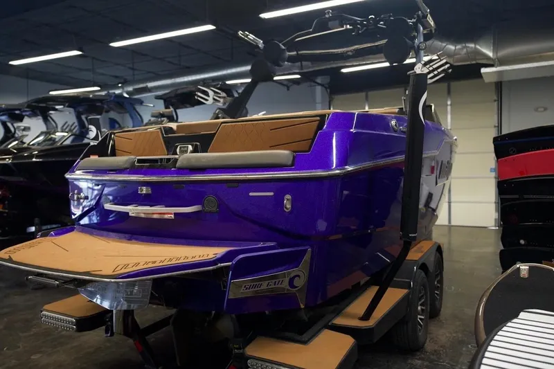 Slide: The Image of 2021 Malibu M220 boat in showroom, vibrant purple exterior, sleek design. - 5