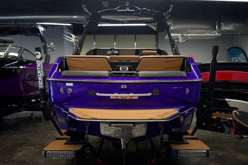Slide: The Image of 2021 Malibu M220 boat, vibrant purple, rear view in showroom setting. - 6