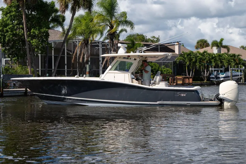 Slide: The Image of 2019 Scout 320 LXF boat on water, surrounded by palm trees and residential docks. - 0