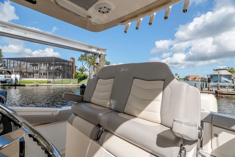 Slide: The Image of 2019 Scout 320 LXF boat interior with luxurious seating, dockside view, and clear blue sky. - 18