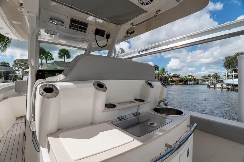 Slide: The Image of 2019 Scout 320 LXF boat interior with sink and seating, docked by waterfront homes. - 20