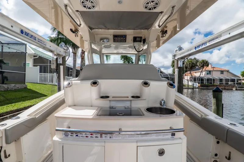 Slide: The Image of 2019 Scout 320 LXF boat interior with sink and seating, docked by waterfront homes. - 22