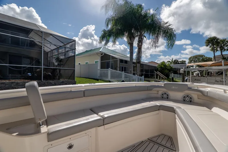Slide: The Image of 2019 Scout 320 LXF boat interior with seating, docked near waterfront homes and palm trees. - 30