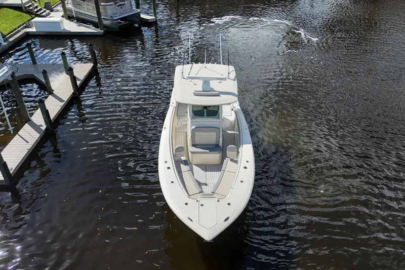 Slide: The Image of 2019 Scout 320 LXF boat navigating a calm waterway near docks. - 7
