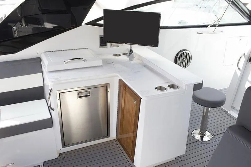 Slide: The Image of 2023 Cruisers Yachts 38 GLS OB interior with seating, counter, and mounted screen. - 12