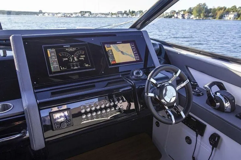 Slide: The Image of 2023 Cruisers Yachts 38 GLS OB helm with advanced navigation displays on a serene lake. - 16