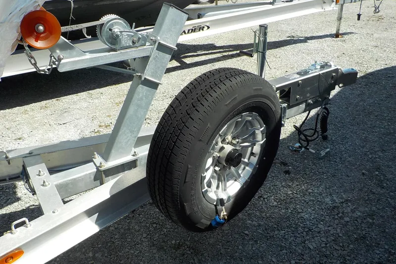 Slide: The Image of Trailer with spare tire for 2022 Edgewater 230CC boat on gravel surface. - 11