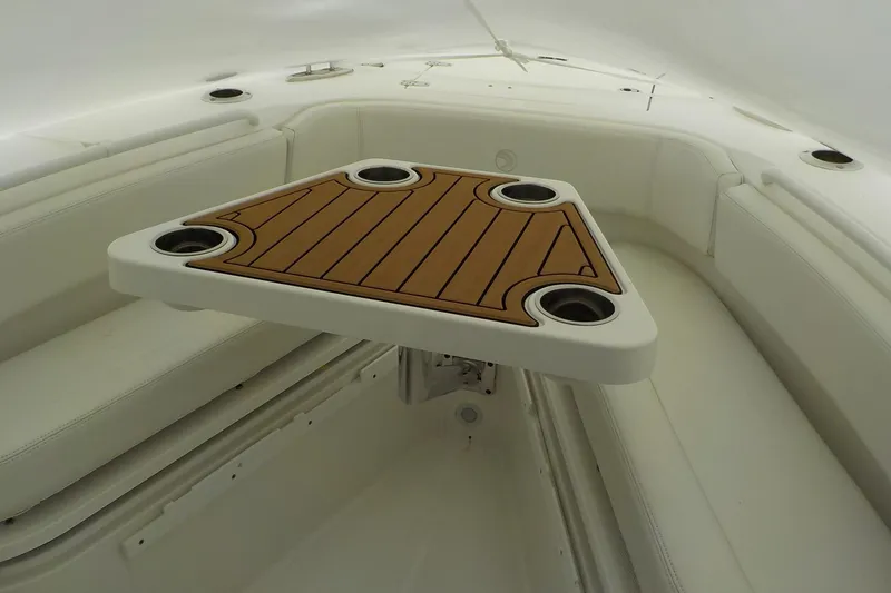 Slide: The Image of Interior of 2022 Edgewater 230CC boat with wooden table and white seating. - 8