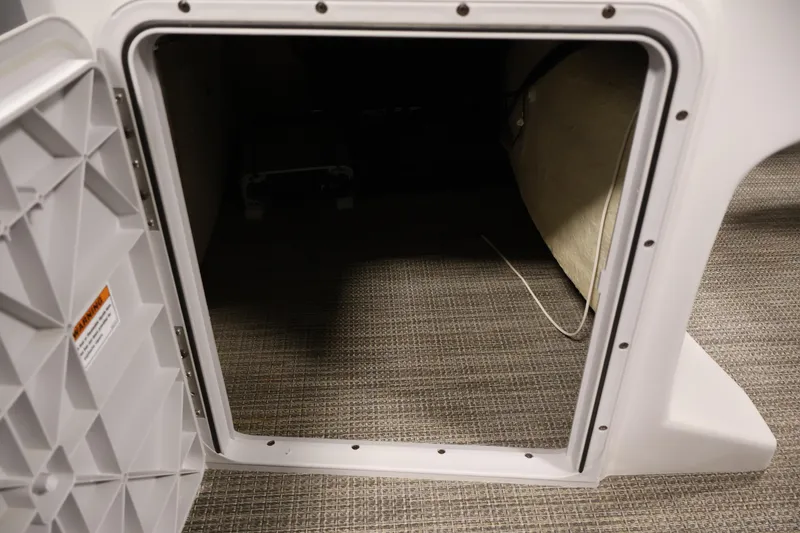 Slide: The Image of Open storage compartment on a 2018 Sweetwater 2186 boat, featuring a carpeted interior. - 18