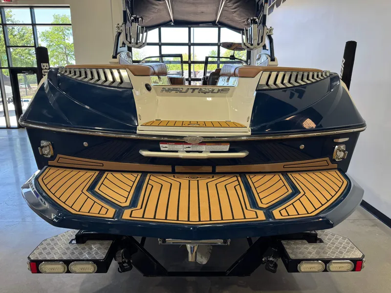 Slide: The Image of Rear view of a 2019 Nautique Super Air Nautique G25 boat in showroom. - 8