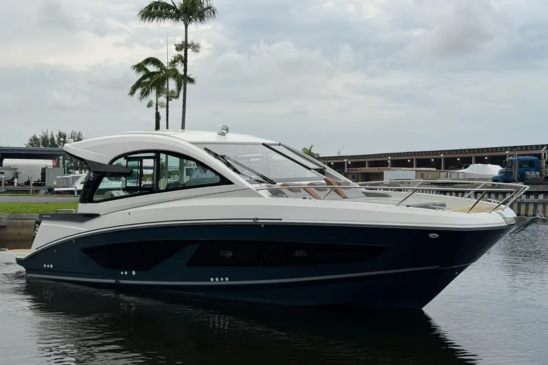 Slide: The Image of 2023 Beneteau Gran Turismo 32 yacht docked, sleek design, overcast sky, palm trees in background. - 48