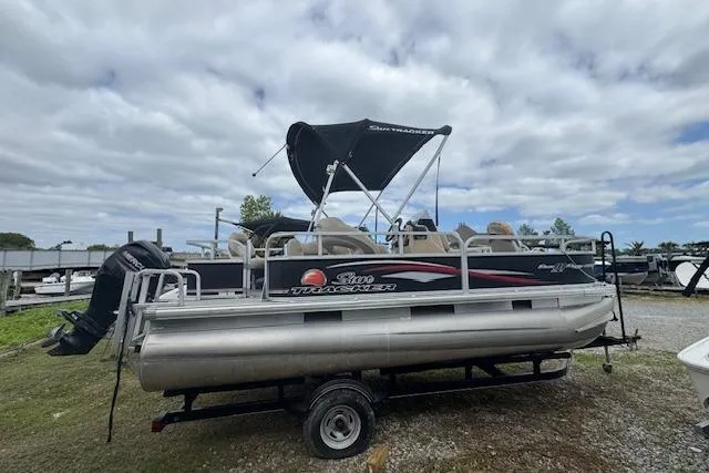 The Image of 2016 Sun Tracker Bass Buggy 18 DLX pontoon boat on trailer under cloudy sky. - 1