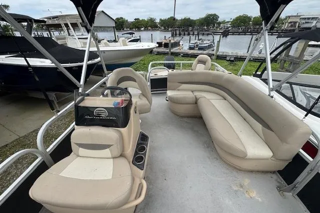 Slide: The Image of 2016 Sun Tracker Bass Buggy 18 DLX pontoon boat with beige seating, docked near other boats. - 8