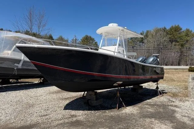 The Image of 2004 Regulator 24 Forward Seating boat on display outdoors, with dual engines and a T-top. - 1