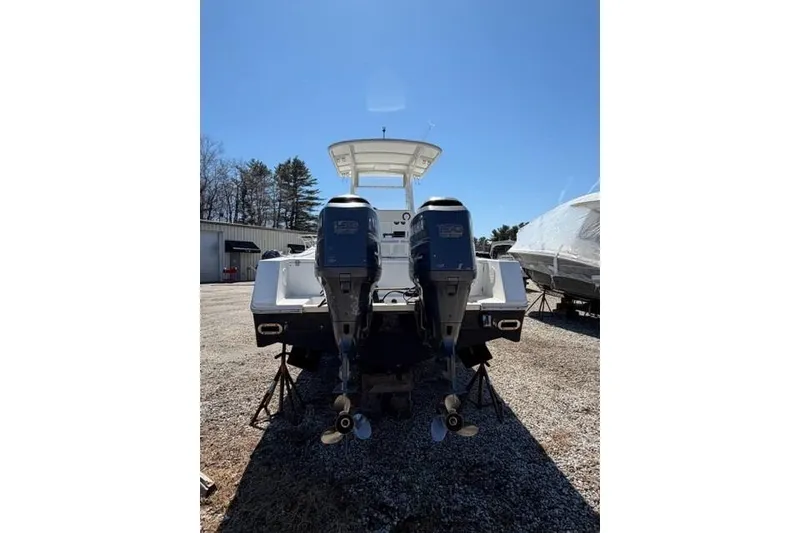 Slide: The Image of 2004 Regulator 24 Forward Seating boat with dual outboard motors, parked outdoors. - 4