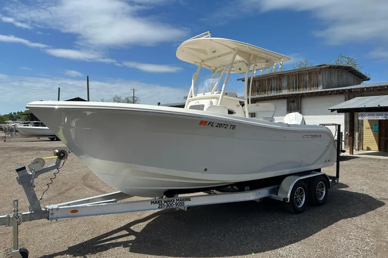 The Image of 2022 Cobia 220 Center Console boat on trailer at marina under blue sky. - 0