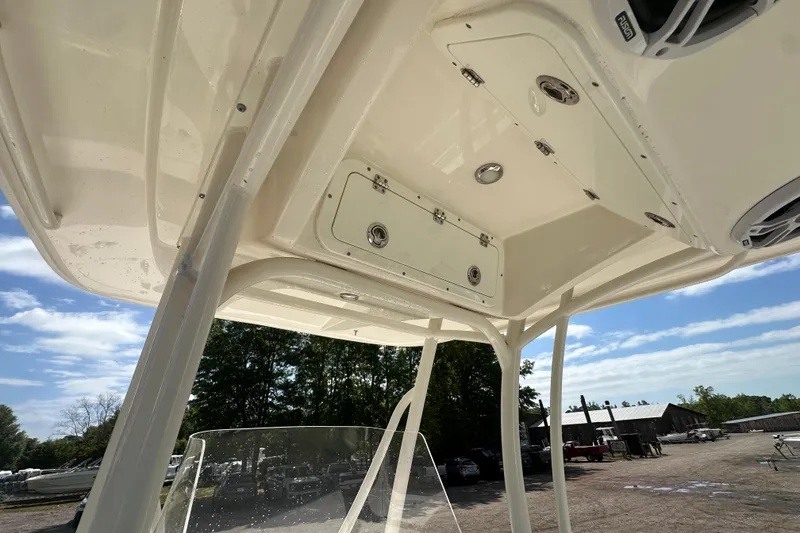 Slide: The Image of 2022 Cobia 220 Center Console boat with overhead storage and speakers, outdoors under blue sky. - 16