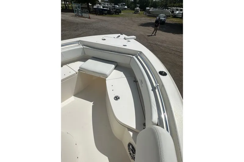 Slide: The Image of 2022 Cobia 220 Center Console boat interior with seating and storage, parked outdoors. - 25