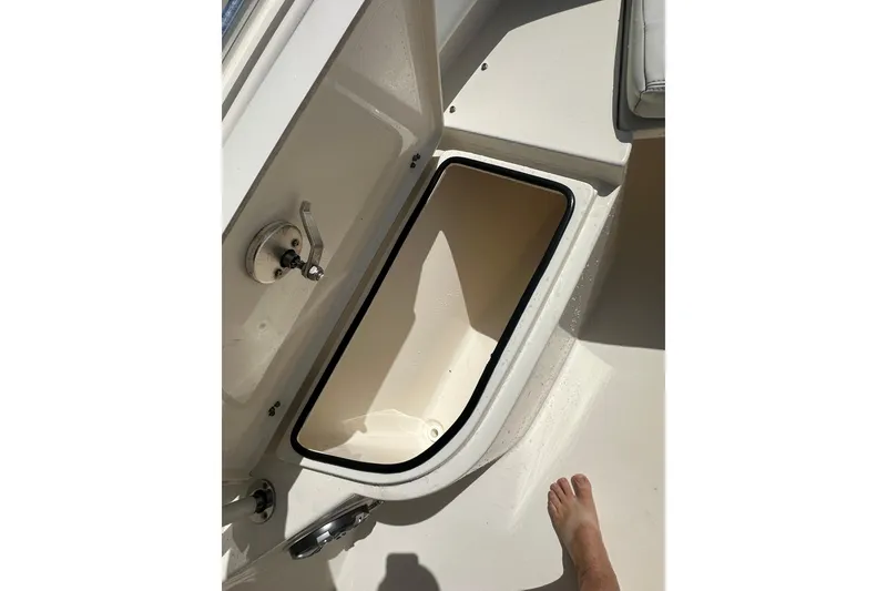 Slide: The Image of 2022 Cobia 220 Center Console boat storage compartment with open lid. - 30