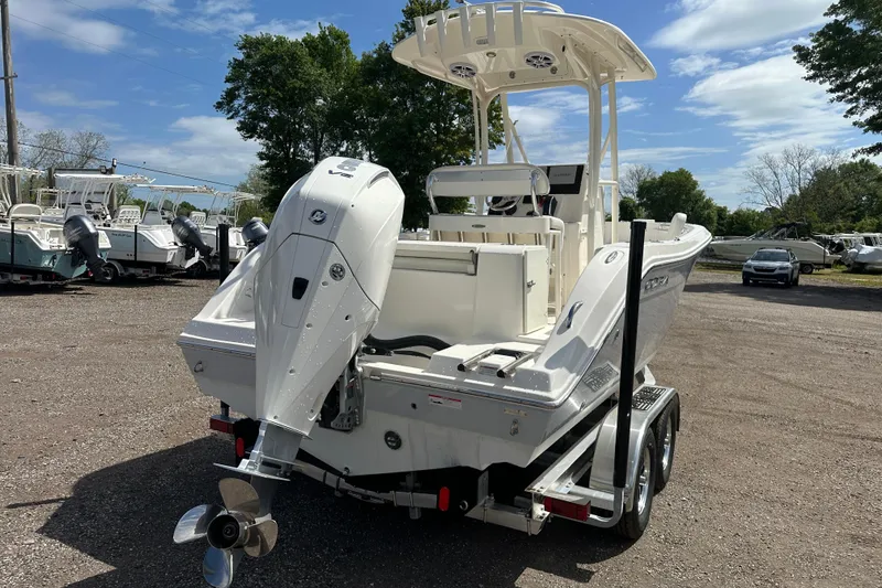 Slide: The Image of 2022 Cobia 220 Center Console boat with outboard motor on trailer, parked outdoors. - 4