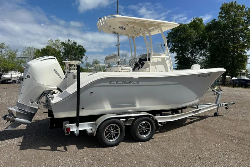 Slide: The Image of 2022 Cobia 220 Center Console boat on trailer, parked outdoors under blue sky. - 6