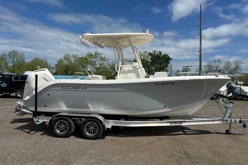 Slide: The Image of 2022 Cobia 220 Center Console boat on trailer, parked outdoors under a blue sky. - 7