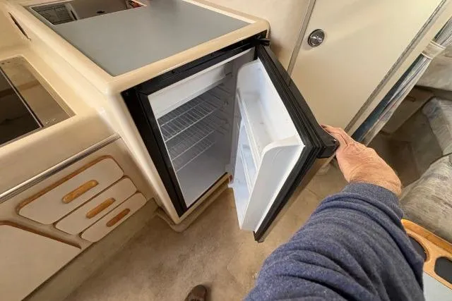 Slide: The Image of 1993 Sea Ray Sundancer 330 interior with open mini fridge in kitchenette area. - 100