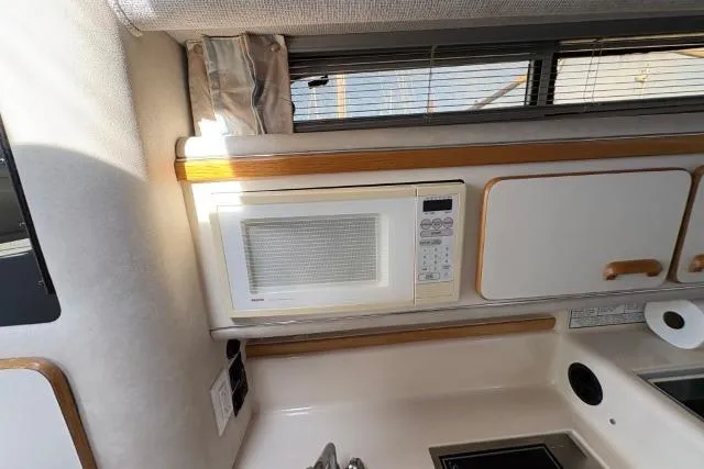 Slide: The Image of 1993 Sea Ray Sundancer 330 galley with microwave, cabinets, and window blinds. - 101