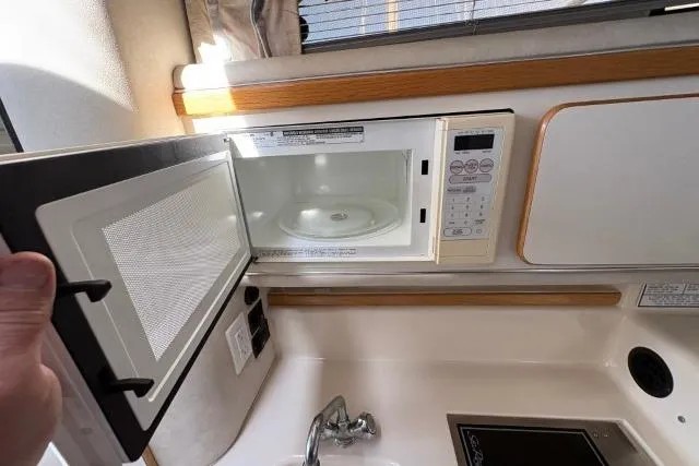 Slide: The Image of 1993 Sea Ray Sundancer 330 kitchen with open microwave and sink. - 102