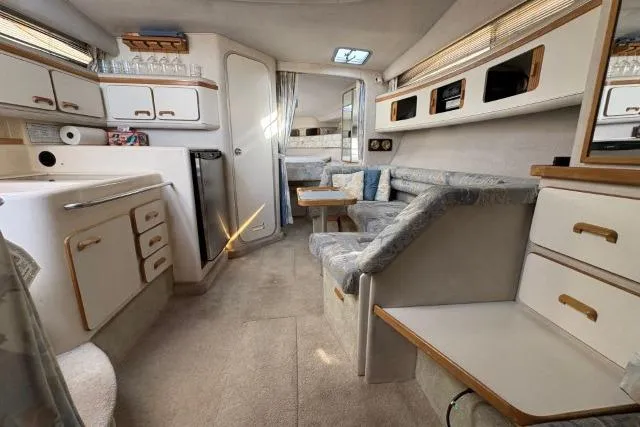 Slide: The Image of Interior of a 1993 Sea Ray Sundancer 330 yacht, featuring a cozy seating area and kitchenette. - 97